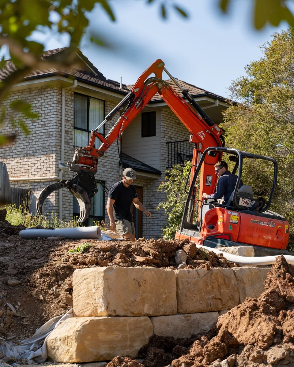 BD Excavation Services crew placing sandstone blocks with an excavator on a Gold Coast retaining wall job