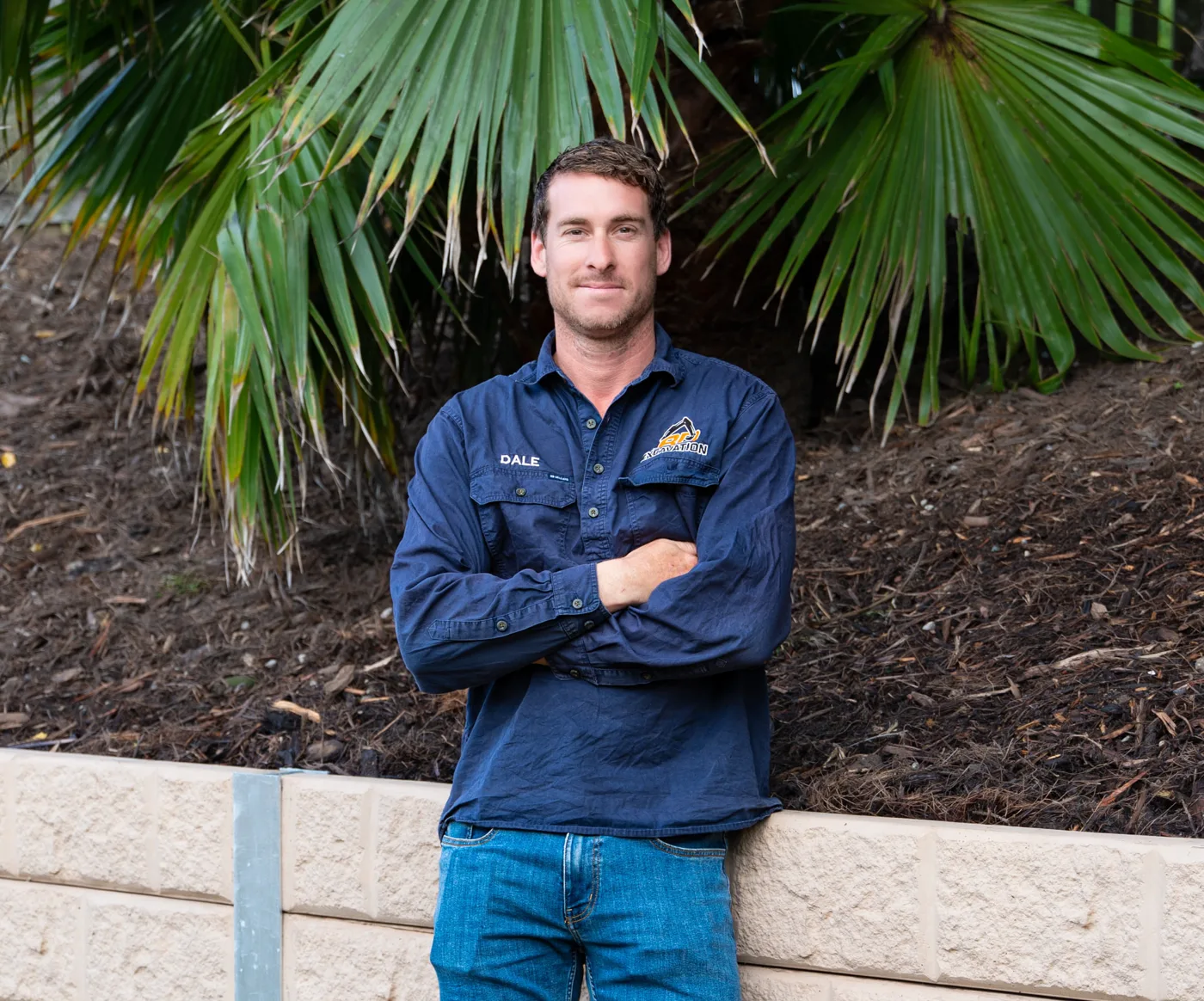 Dale, excavation operator at BD Excavation Services, standing beside a completed retaining wall